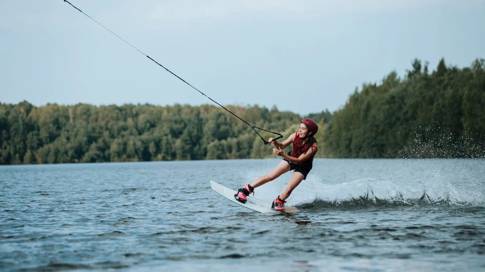 Woman enjoying an exhilarating wakeboarding session on a scenic lake.