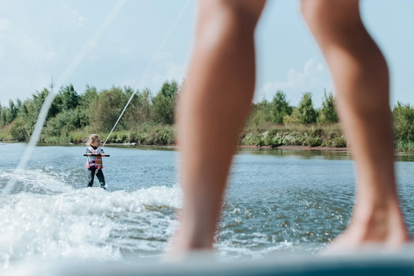 Young girl wakeboarding on a sunny summer day, showcasing outdoor fun and adventure.